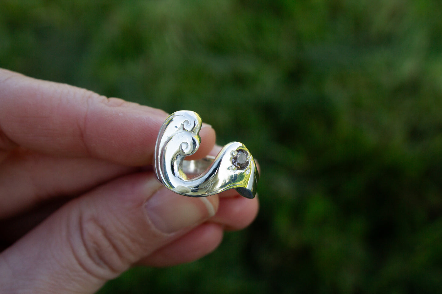 one of a kind sterling silver and spinel sculptural ring handmade Ireland held in fingers on a green background