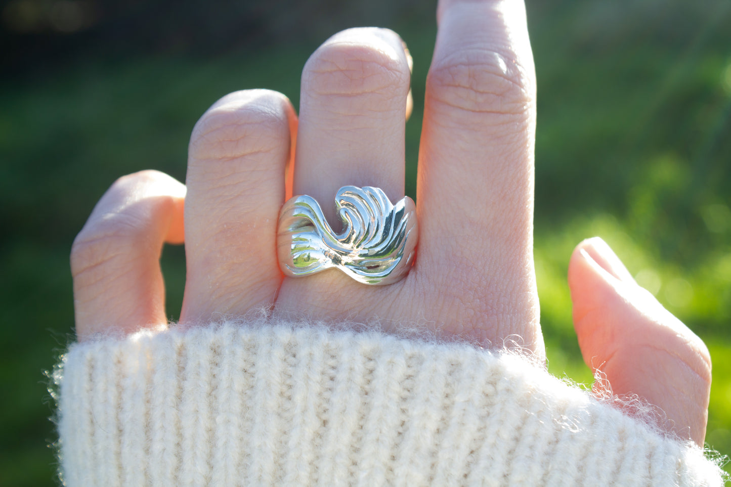 one of a kind sterling silver sculptural ring handmade Ireland worn on the middle finger on a green background