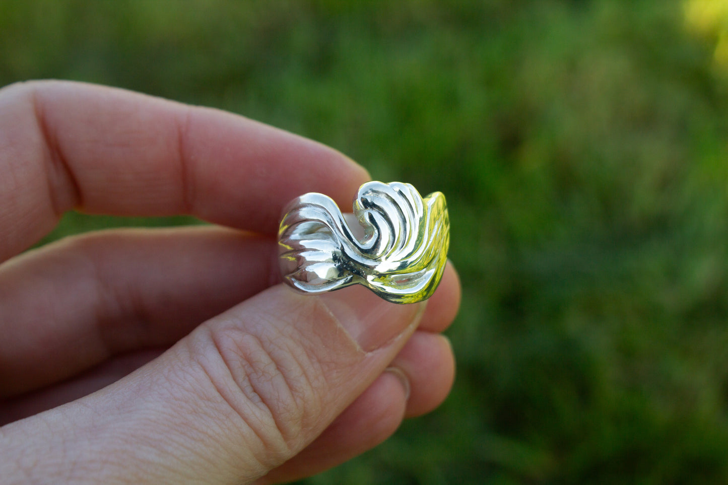 one of a kind sterling silver sculptural ring handmade Ireland held in fingers on a green background